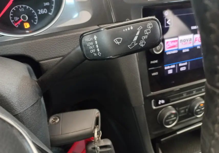 Gros plan sur la commande d’essuie-glace et le tableau de bord noir d’une Volkswagen Golf gris foncé de 2019.