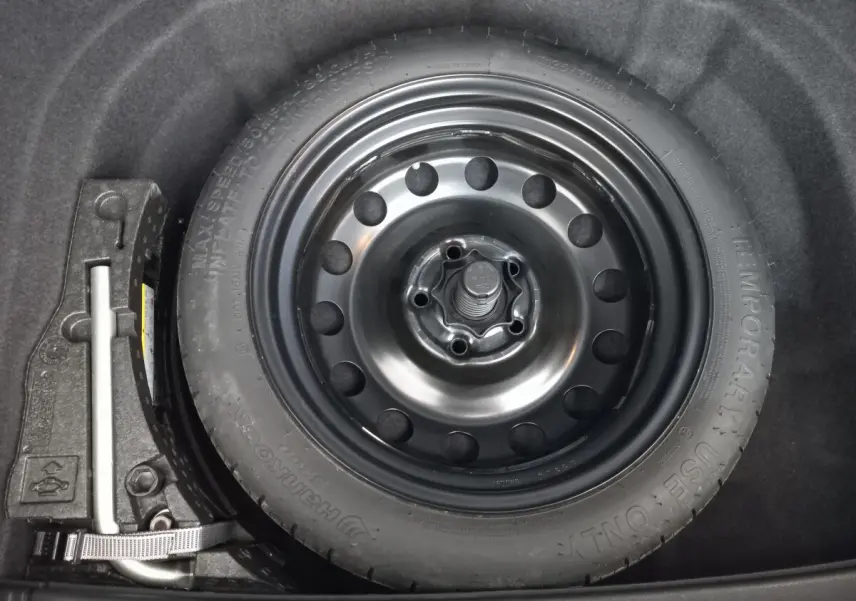 Roue galette noire de secours dans le coffre d'une Volkswagen Golf 1.0 TSI 115 DSG7 Confort Business gris foncé.