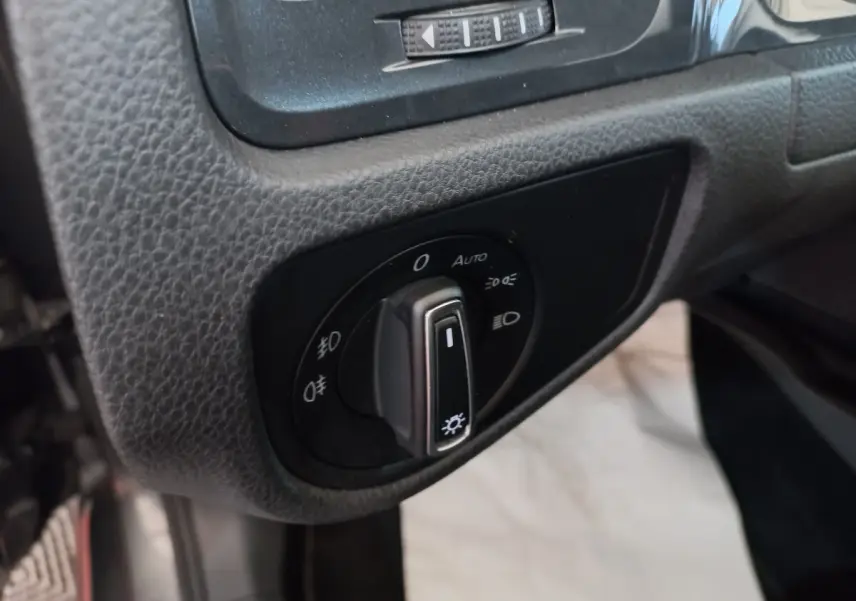 Gros plan sur le bouton de commande des phares dans l'habitacle d'une Volkswagen Golf gris foncé 2019.