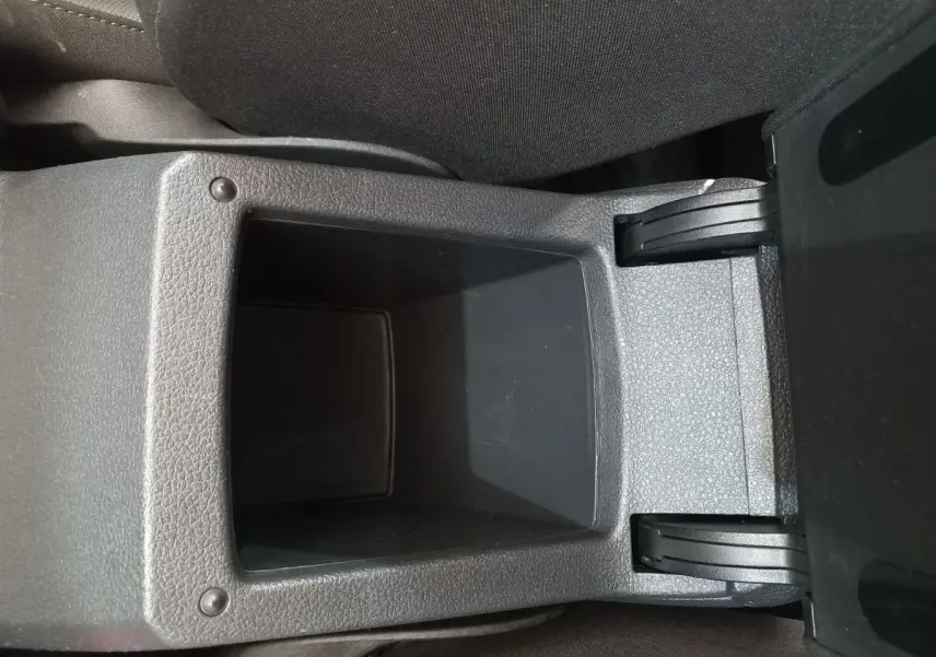 Gros plan sur le rangement central ouvert entre les sièges avant d'une Volkswagen Golf gris foncé de 2019.