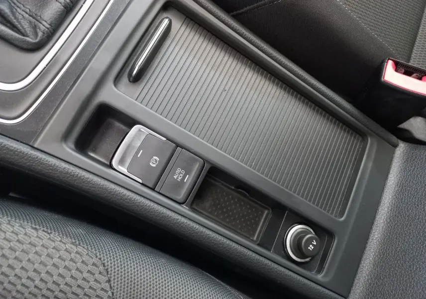 Gros plan sur la console centrale noire de la Volkswagen Golf 1.0 TSI 2019 avec frein à main électrique et prise 12V.