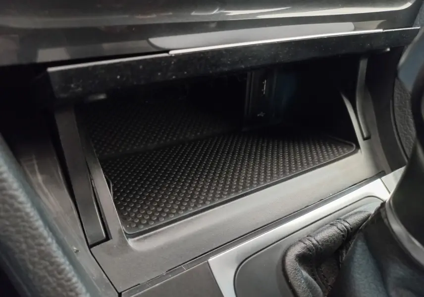Rangement ouvert côté passager avec prise USB et console centrale en cuir noir dans une Volkswagen Golf gris foncé 2019.