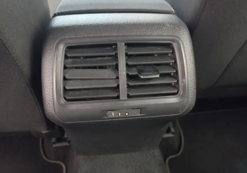 Grille d'aération arrière noire de la Volkswagen Golf gris foncé, vue centrée entre les sièges arrière.