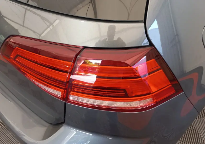 Gros plan sur le feu arrière droit rouge d'une Volkswagen Golf gris foncé, vue arrière en intérieur.