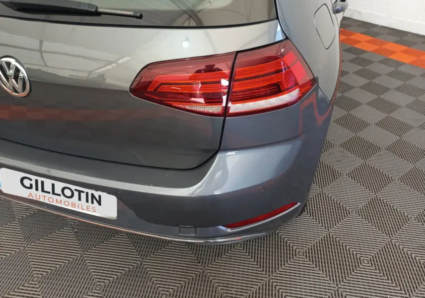 Vue rapprochée arrière droite d'une Volkswagen Golf gris foncé avec feux arrière LED et logo VW visible.