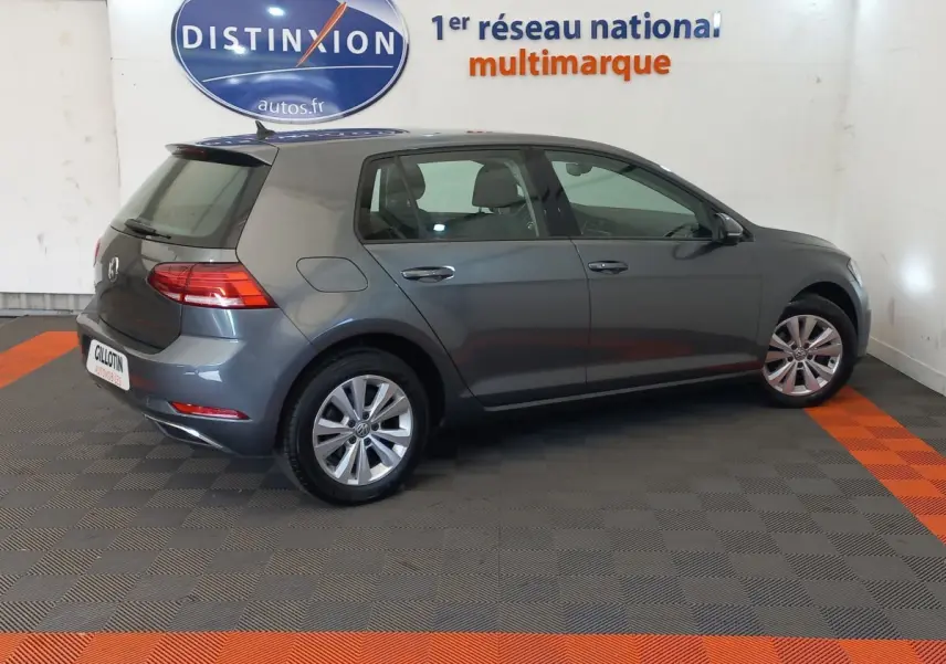 Volkswagen Golf gris foncé vue de profil côté droit dans un showroom avec logo Distinxion en arrière-plan