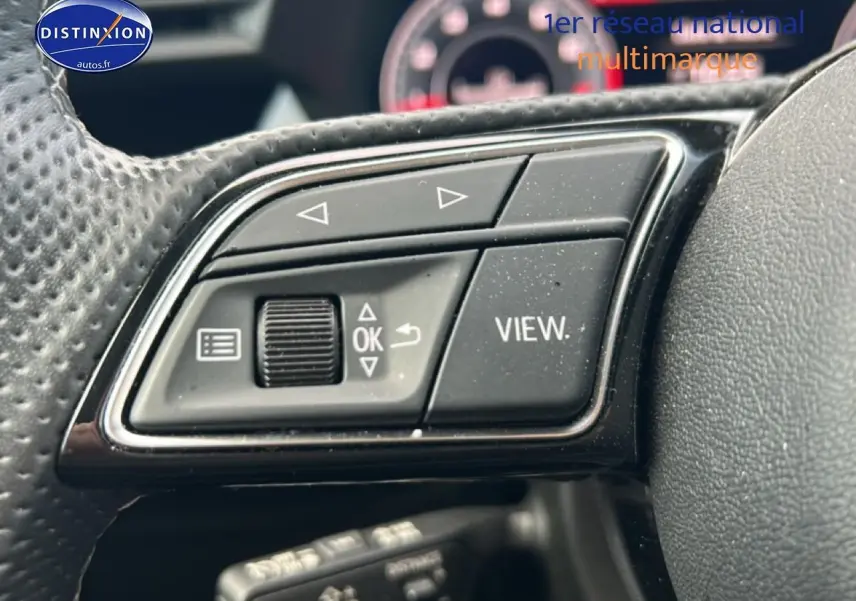 Gros plan sur les commandes multifonctions noires du volant cuir de l'Audi A3 Sportback 2024, version S line.