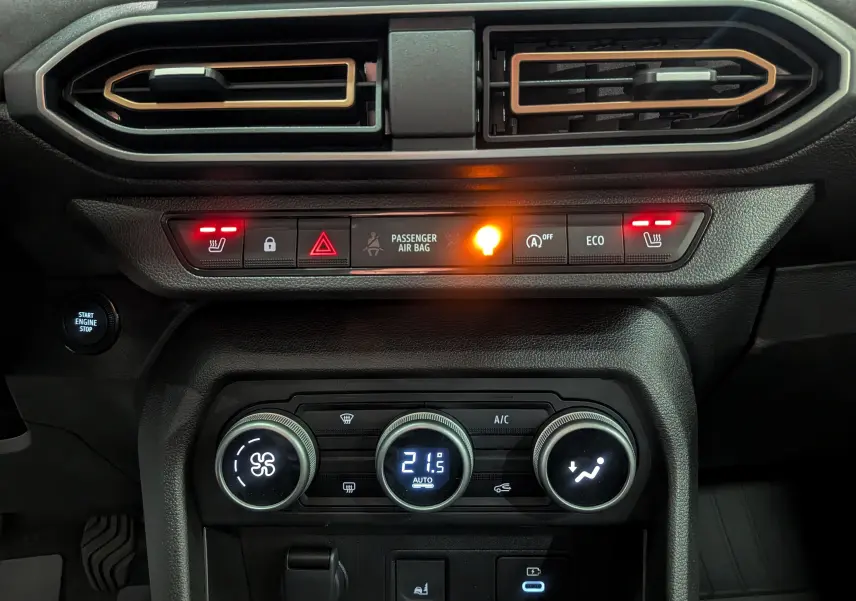 Vue rapprochée du tableau de bord noir de la Dacia Sandero Stepway 2025, avec commandes climatisation et sièges chauffants allumés.