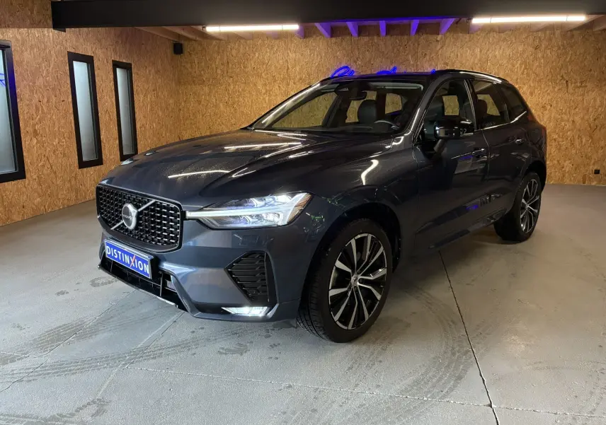 Vue 3/4 avant droite d'un Volvo XC60 bleu avec calandre noire laquée et jantes alliage 20 pouces bicolores.
