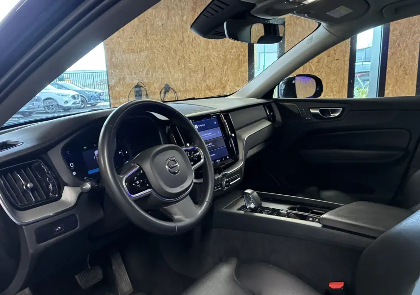 Intérieur noir du Volvo XC60 2023 vu côté conducteur, avec tableau de bord digital et console centrale moderne.