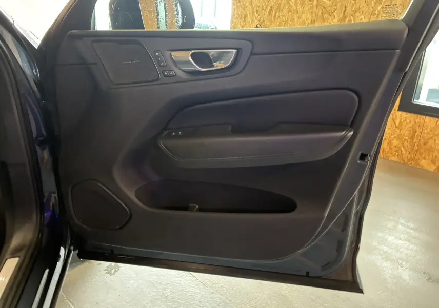 Vue intérieure côté gauche de la porte avant bleu foncé du Volvo XC60 2023 avec haut-parleur Harman Kardon intégré.