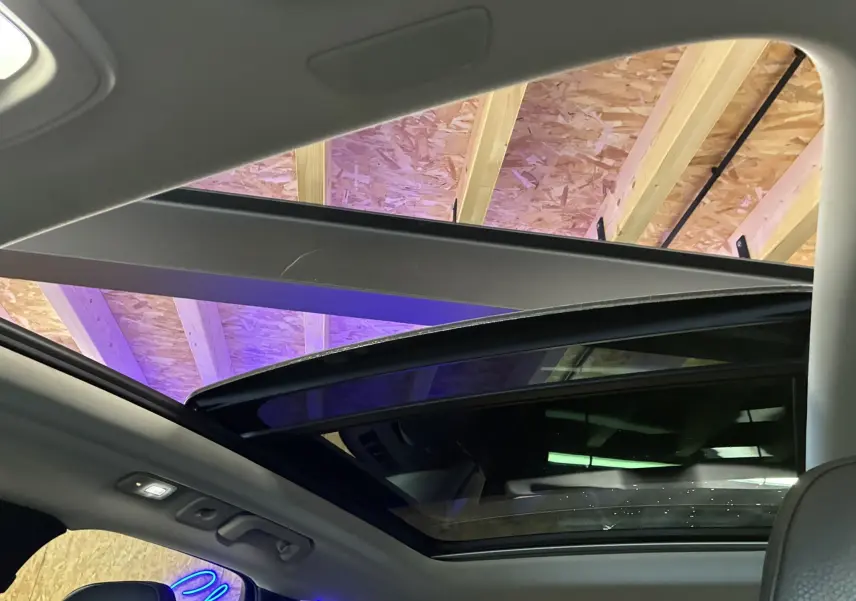 Toit ouvrant panoramique ouvert vu de l'intérieur d'un Volvo XC60 2023, sellerie cuir grise visible.