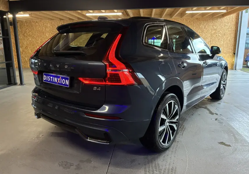 Vue 3/4 arrière droite du Volvo XC60 bleu 2023 avec feux arrière LED et jantes alliage 20 pouces noir diamant.