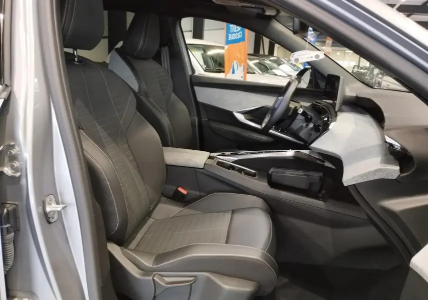 Vue intérieure côté conducteur du Peugeot 3008 gris Artense 2024, mettant en valeur les sièges et le tableau de bord moderne.