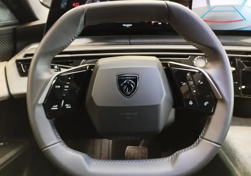 Vue rapprochée du volant cuir gris du Peugeot 3008 2024 avec logo lion et commandes intégrées noir laqué.