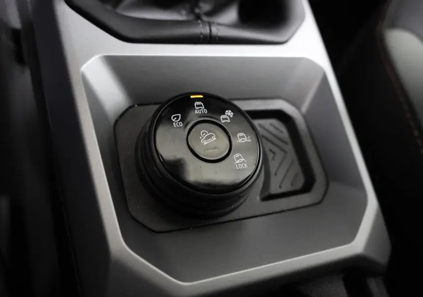 Gros plan sur la molette de sélection des modes de conduite du Dacia Duster TCE 130 4x4, intérieur gris et noir.
