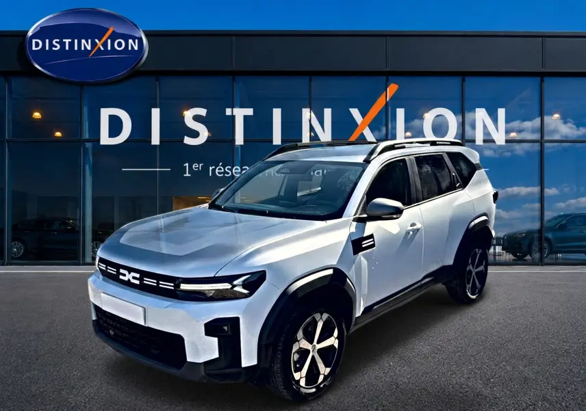 SUV Dacia Bigster blanc en 3/4 avant droit, avec barres de toit et jantes alu noires et argentées.