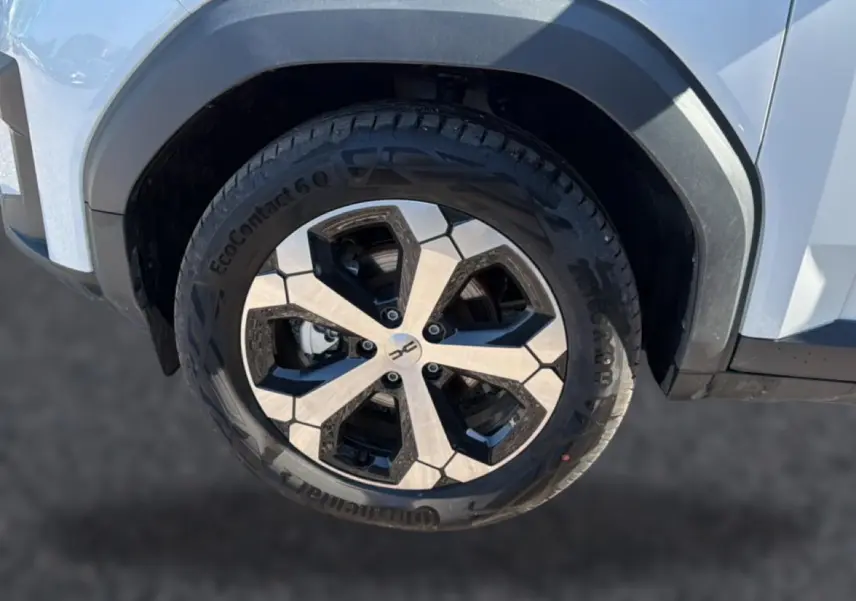 Gros plan sur la roue avant droite du Dacia Bigster blanc, mettant en valeur la jante alu au design géométrique.