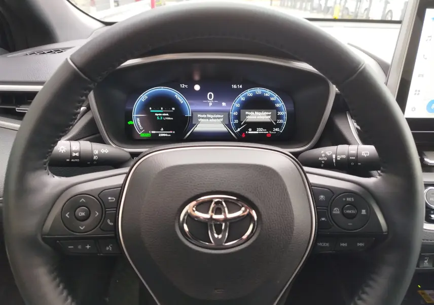 Vue centrée sur le volant noir et le tableau de bord numérique éclairé de la Toyota Corolla Cross Hybrid 2025.