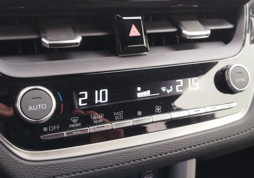Gros plan sur la console de climatisation digitale de la Toyota Corolla Cross Hybrid 140 Luxury Limited, affichant 21°C à gauche et 21,5°C à droite.