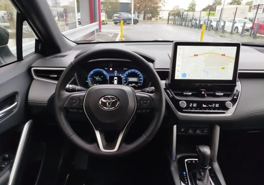 Vue intérieure centrée sur le volant et le tableau de bord numérique d’une Toyota Corolla Cross Hybrid 140 Luxury Limited noir.