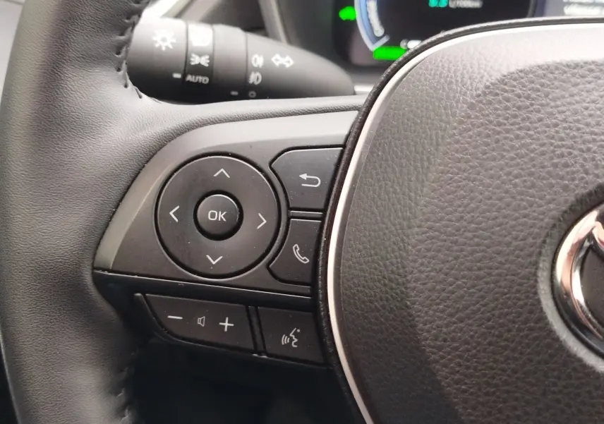 Gros plan sur les commandes multifonctions à gauche du volant noir du Toyota Corolla Cross Hybrid 140 Luxury Limited 2025.