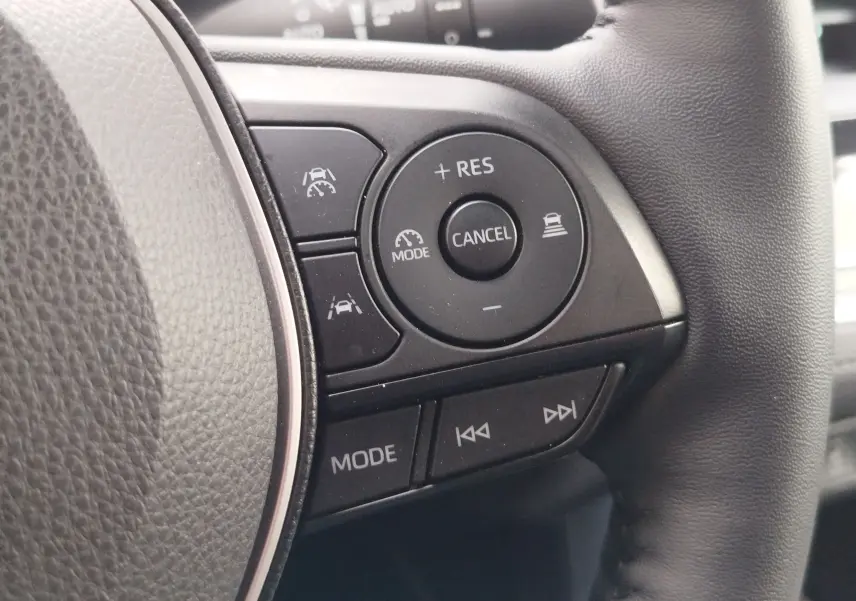 Gros plan sur les commandes au volant côté droit du Toyota Corolla Cross Hybrid 140 Luxury Limited 2025, finition noire.