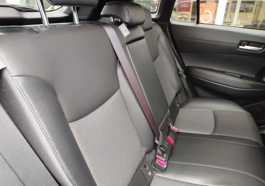 Vue intérieure côté droit des sièges arrière en cuir noir et tissu gris de la Toyota Corolla Cross Hybrid 140 Luxury Limited 2025.