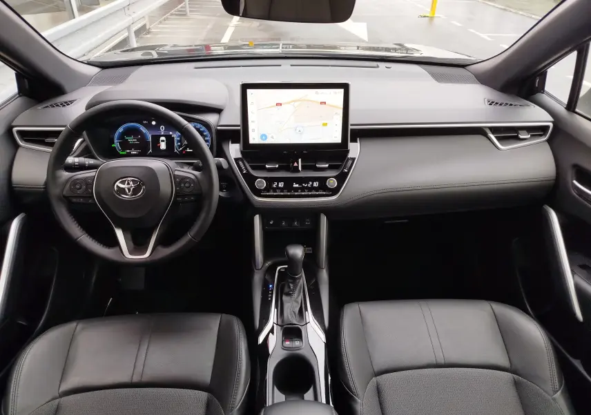 Vue intérieure avant de la Toyota Corolla Cross Hybrid 140 Luxury Limited 2025, tableau de bord noir avec écran tactile central et volant multifonction.