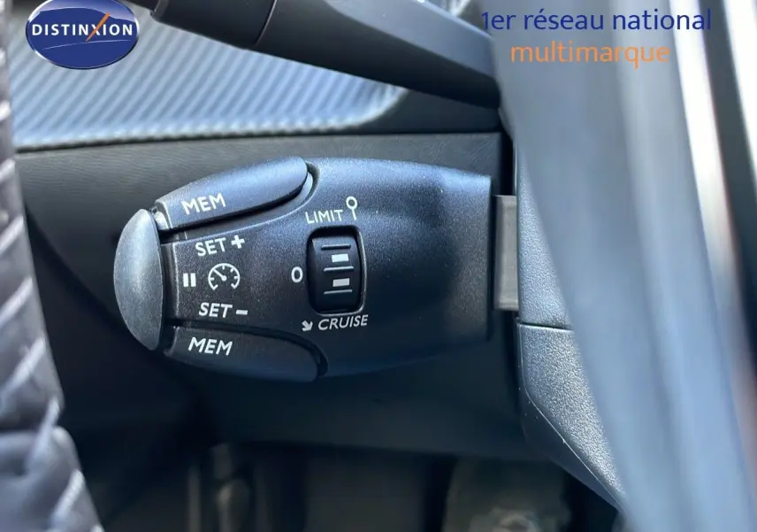 Gros plan sur la commande de régulateur de vitesse à gauche du volant d’un Peugeot 2008 gris Artense Metal.