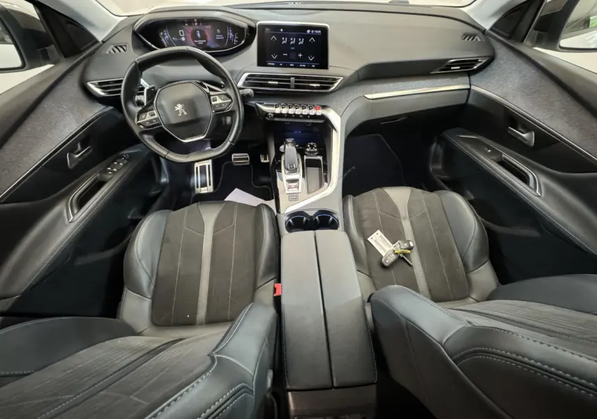 Intérieur noir du Peugeot 3008 2019 vu de dessus, avec volant cuir, console centrale et clés sur siège passager.