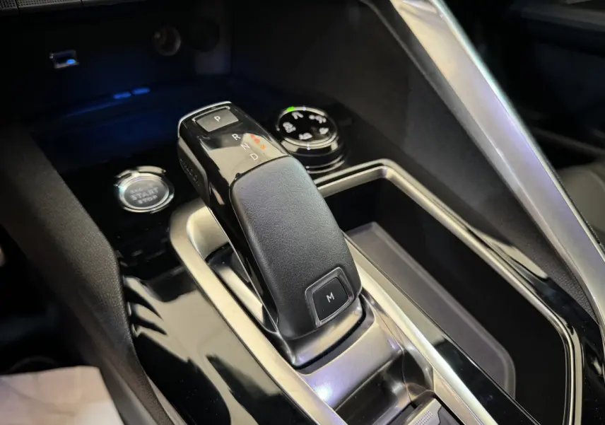 Le levier de vitesse automatique noir et cuir du Peugeot 3008 blanc, vu en gros plan intérieur central.