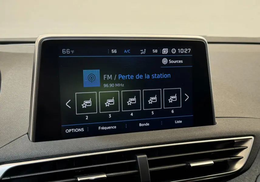 Écran tactile central affichant la radio FM dans l'habitacle du Peugeot 3008 blanc, vue rapprochée du tableau de bord.