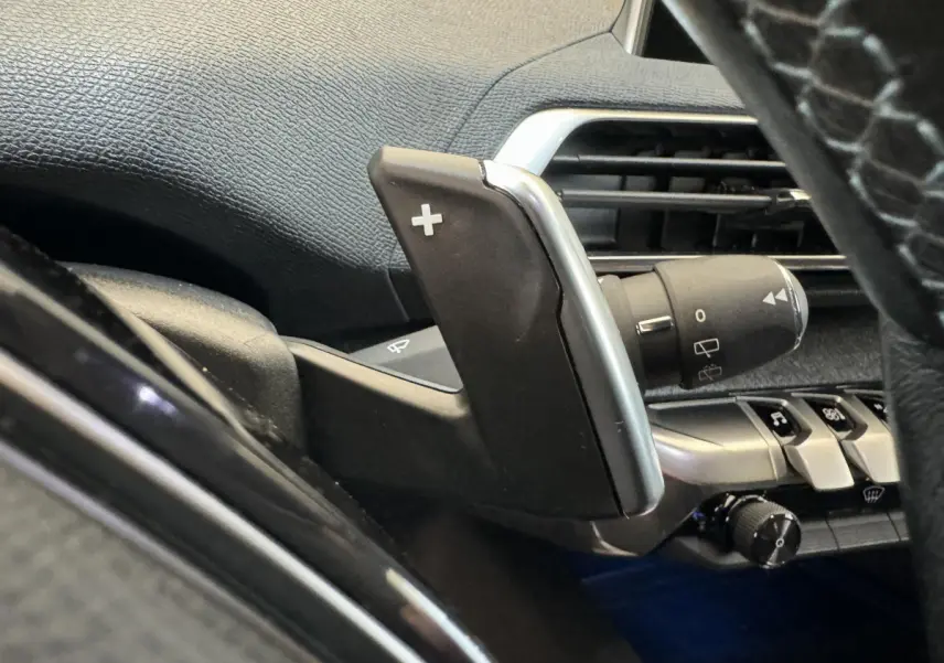 Gros plan sur la palette de changement de vitesse droite noire et argentée dans le tableau de bord intérieur du Peugeot 3008 blanc.