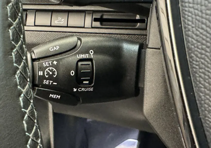 Gros plan sur la commande de régulateur de vitesse à gauche du volant du Peugeot 3008 blanc, version Crossway.