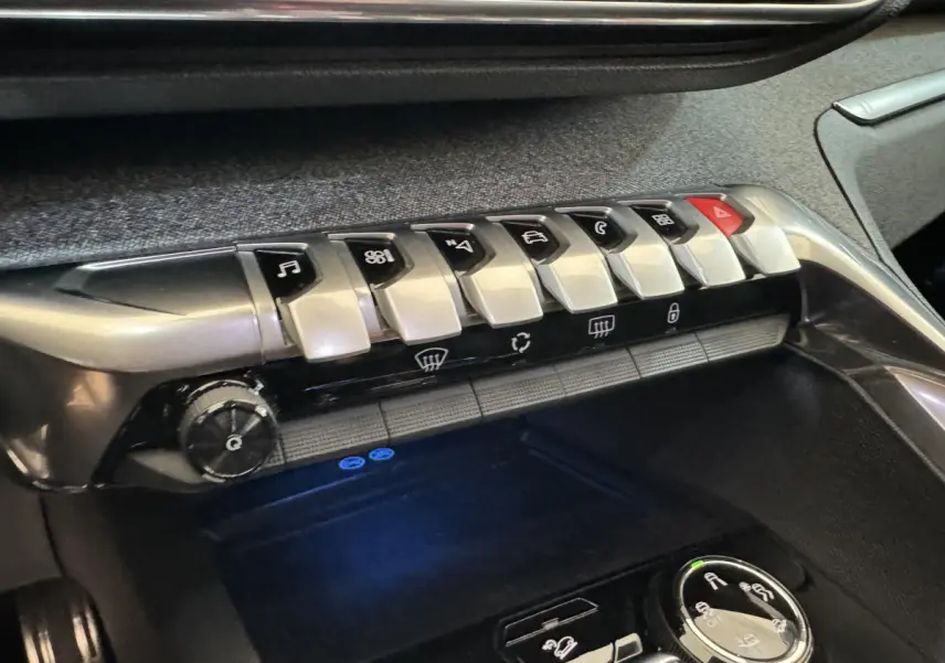 Gros plan sur la console centrale du Peugeot 3008 blanc 2019, montrant les commandes tactiles et boutons argentés du tableau de bord.