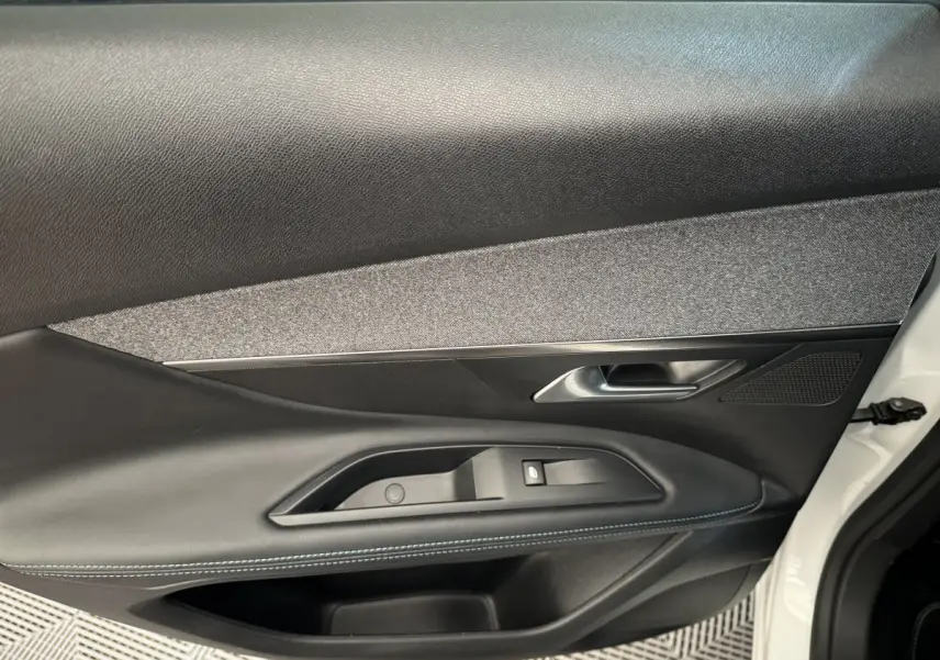 Gros plan sur la porte avant droite blanche du Peugeot 3008 avec garniture noire et surpiqûres bleues.