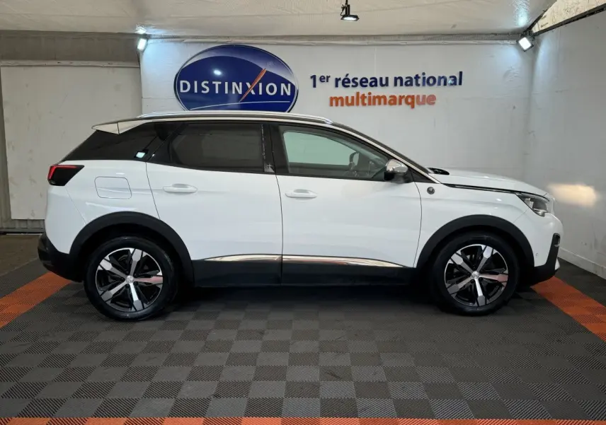 Vue latérale droite d'un Peugeot 3008 blanc avec jantes noires et toit noir dans un showroom.