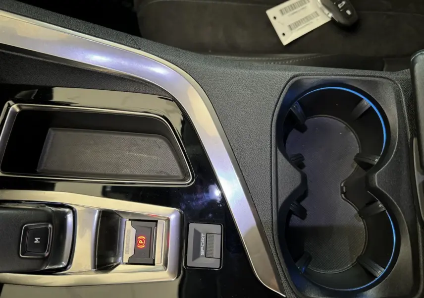 Gros plan sur la console centrale noire du Peugeot 3008 avec bouton Sport et frein à main électrique allumé.