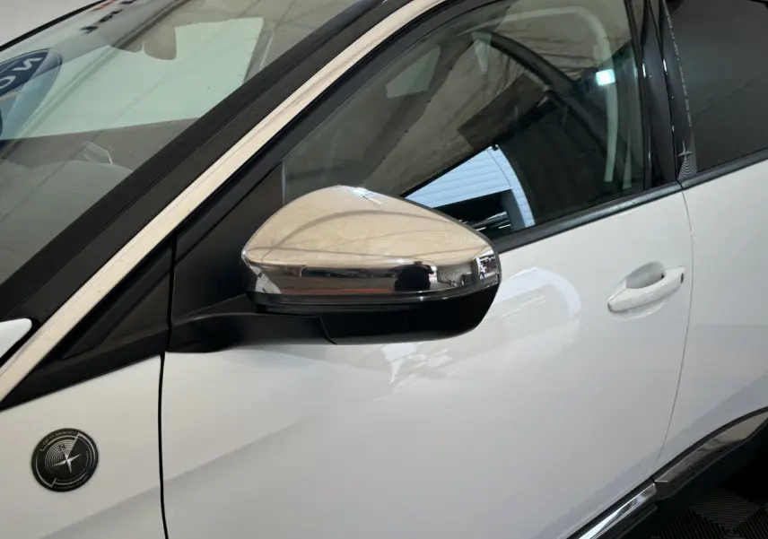 Gros plan sur le rétroviseur chromé côté gauche d'un Peugeot 3008 blanc avec logo spécifique sur la portière.