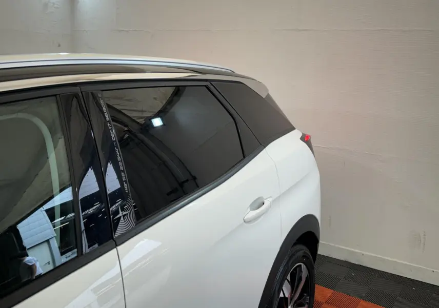 Vue arrière côté droit du Peugeot 3008 blanc avec vitres teintées et jante alliage visible en intérieur fermé.