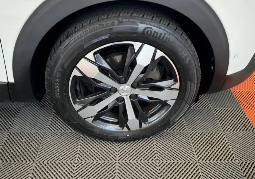 Gros plan sur la roue avant droite blanche d'un Peugeot 3008 avec jante alliage noire et argentée design moderne.