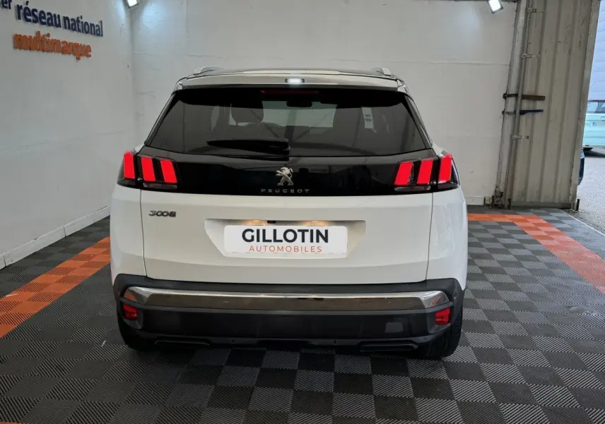 Vue arrière d'un Peugeot 3008 blanc avec feux arrière LED distinctifs et logo central sur bande noire.