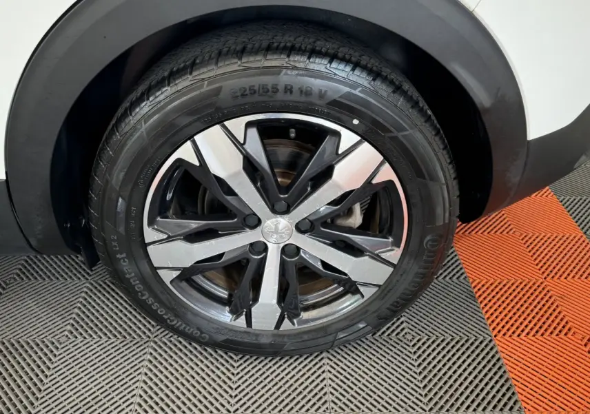 Gros plan sur la roue avant gauche du Peugeot 3008 blanc, mettant en valeur la jante alliage au design moderne.