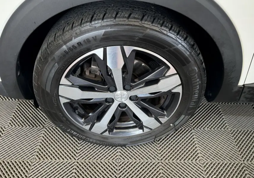Gros plan sur la roue avant droite d'un Peugeot 3008 blanc, jante alliage bicolore et pneu Continental.
