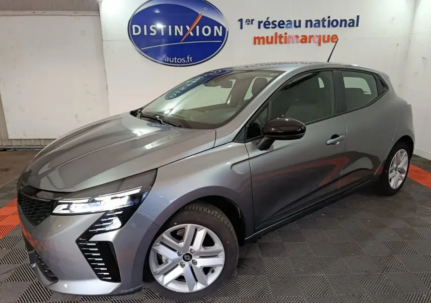 Renault Clio Evolution Blue dCi 100 gris foncé vue 3/4 avant droit avec phares LED allumés en intérieur showroom.