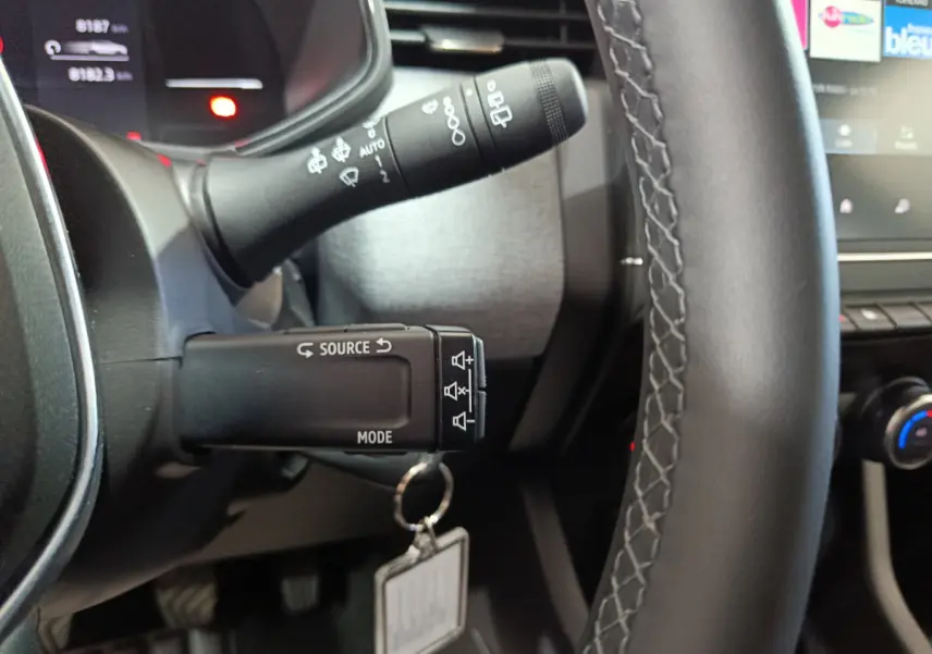 Gros plan sur la commande multifonctions à gauche du volant cuir de la Renault Clio gris foncé 2025.