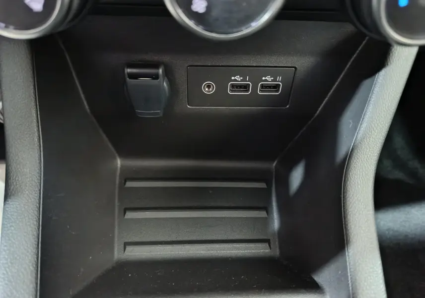Gros plan sur la console centrale noire de la Renault Clio 2025 montrant deux ports USB et une prise jack.