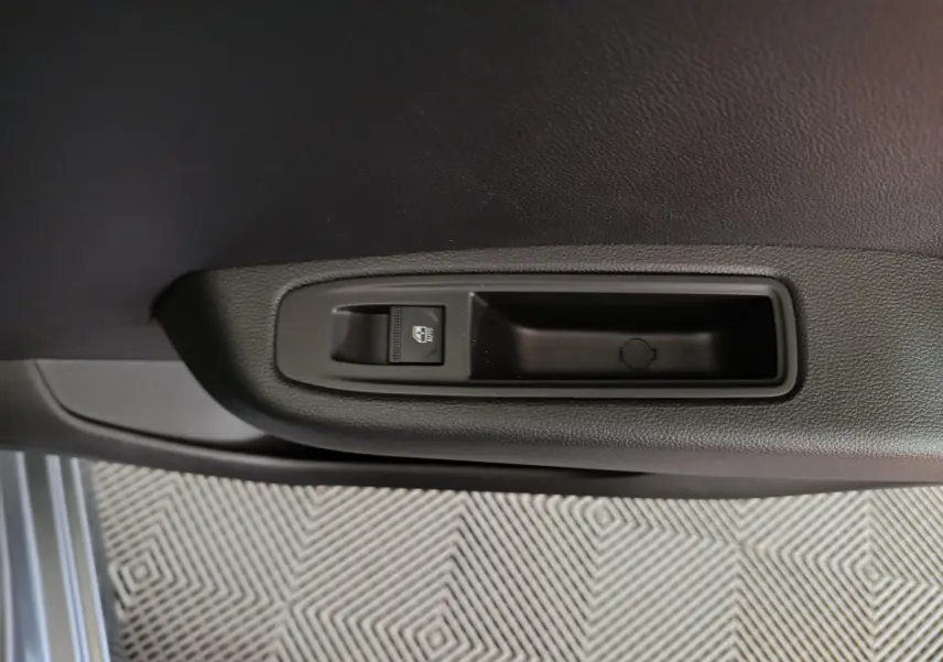 Gros plan sur la commande de lève-vitre côté conducteur de la Renault Clio gris foncé Evolution Blue dCi 2025.