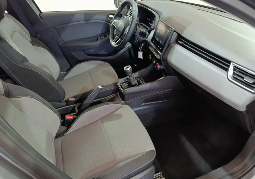 Intérieur avant droit de la Renault Clio gris foncé 2025, montrant sièges tissu, volant multifonctions et écran tactile central.